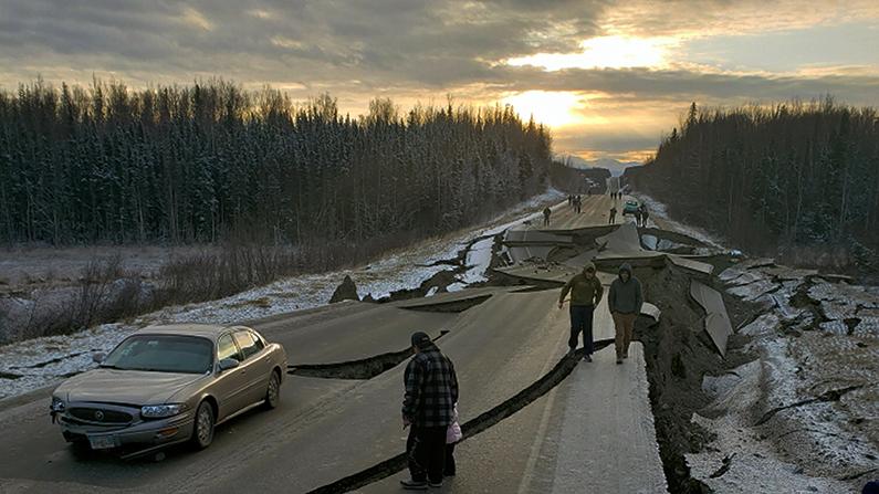 People walk along Vine Road in Wasilla, Alaska, after the 7.0 earthquake, on Nov. 30, 2018, (Jonathan M. Lettow via AP)