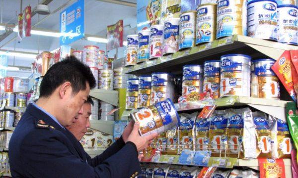 Chinese enforcement officers check the dates on the tins of milk powder at a shop in Tongzi, southwest China's Guizhou region, on February 9, 2010. (AFP/Getty Images)