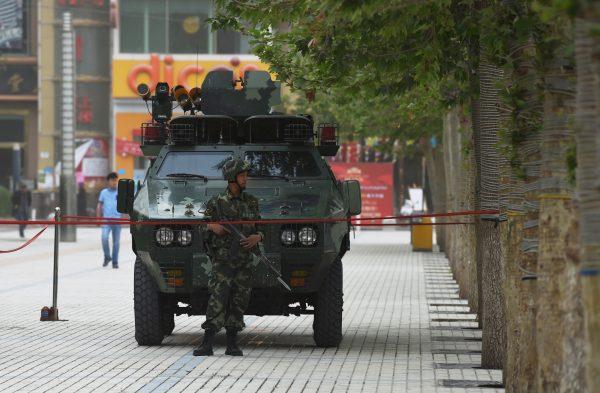 The undated photo shows a member of the Chinese paramilitary police in front of an armored vehicle in Hotan, Xinjiang region of China. The Chinese regime has deepened its suppression of the Uyghur ethnic group in the region. (Greg Baker/AFP/Getty Images)