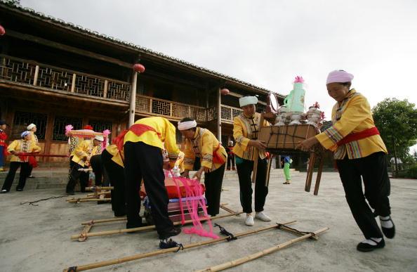 Tujia ethnic people prepare to carry the bride's dowry to the home of the groom during a wedding in Qianjiang Tujia and Miao Autonomous County of Chongqing Municipality, China, on Aug. 2, 2008. (China Photos/Getty Images)