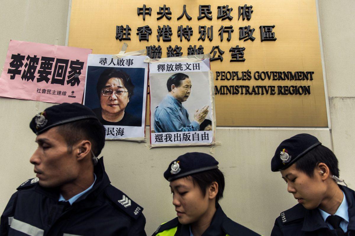 Police walk past missing person notices of Gui Minhai (L) and Yau Wentian (R) in Hong Kong on Jan. 3, 2016. (Anthony Wallace/AFP/Getty Images)