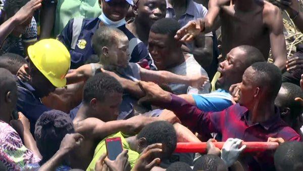 In this image taken from video, people help a child after he was rescued from the scene of a building collapse in Lagos, Nigeria, on March 13, 2019. (AP Photo)