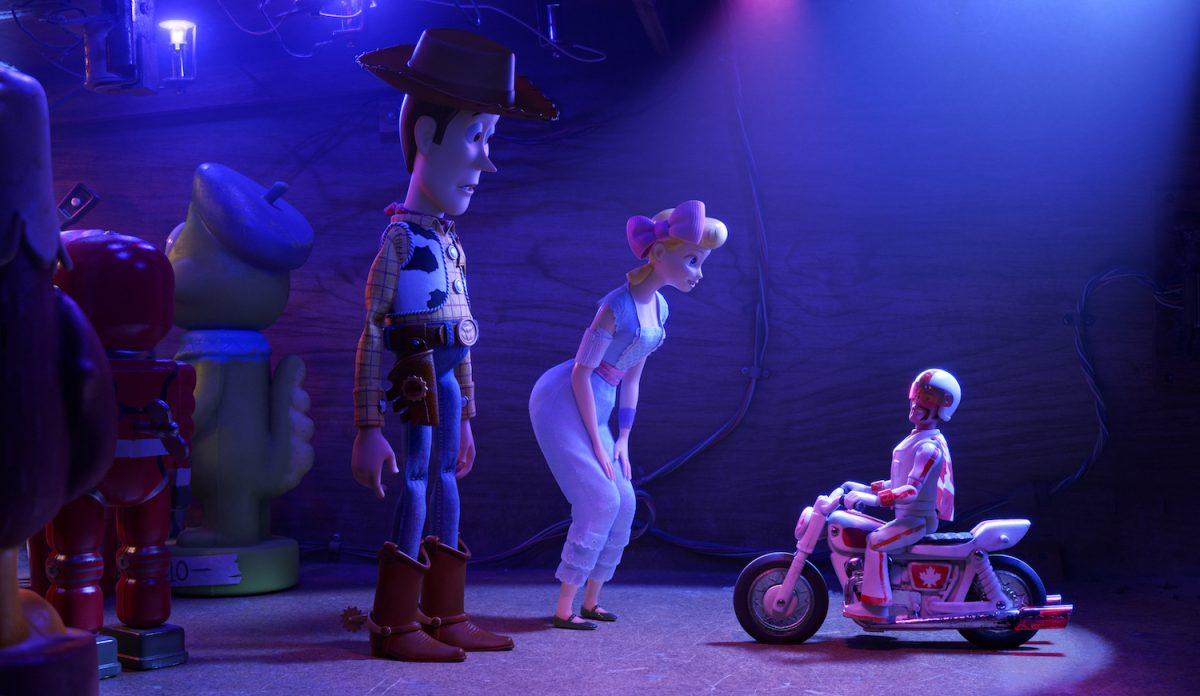 (L–R) Woody (voiced by Tom Hanks), Bo Peep (voiced by Annie Potts), and Duke Caboom (voiced by Keanu Reeves). Woody and Bo turn to Duke Caboom for help, and give him a pep talk to do his best stunt. (Disney/Pixar)