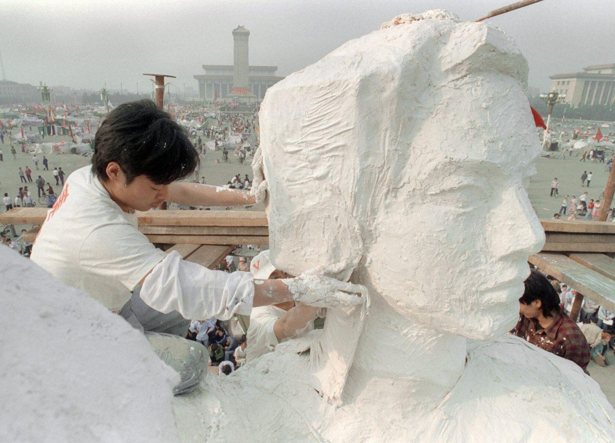 A student from an art institute plasters the neck of the "Goddess of Democracy" statue, a replica of New York's Statue of Liberty in Tiananmen Square in Beijing, on May 30, 1989. (Catherine Henriette/AFP/Getty Images)