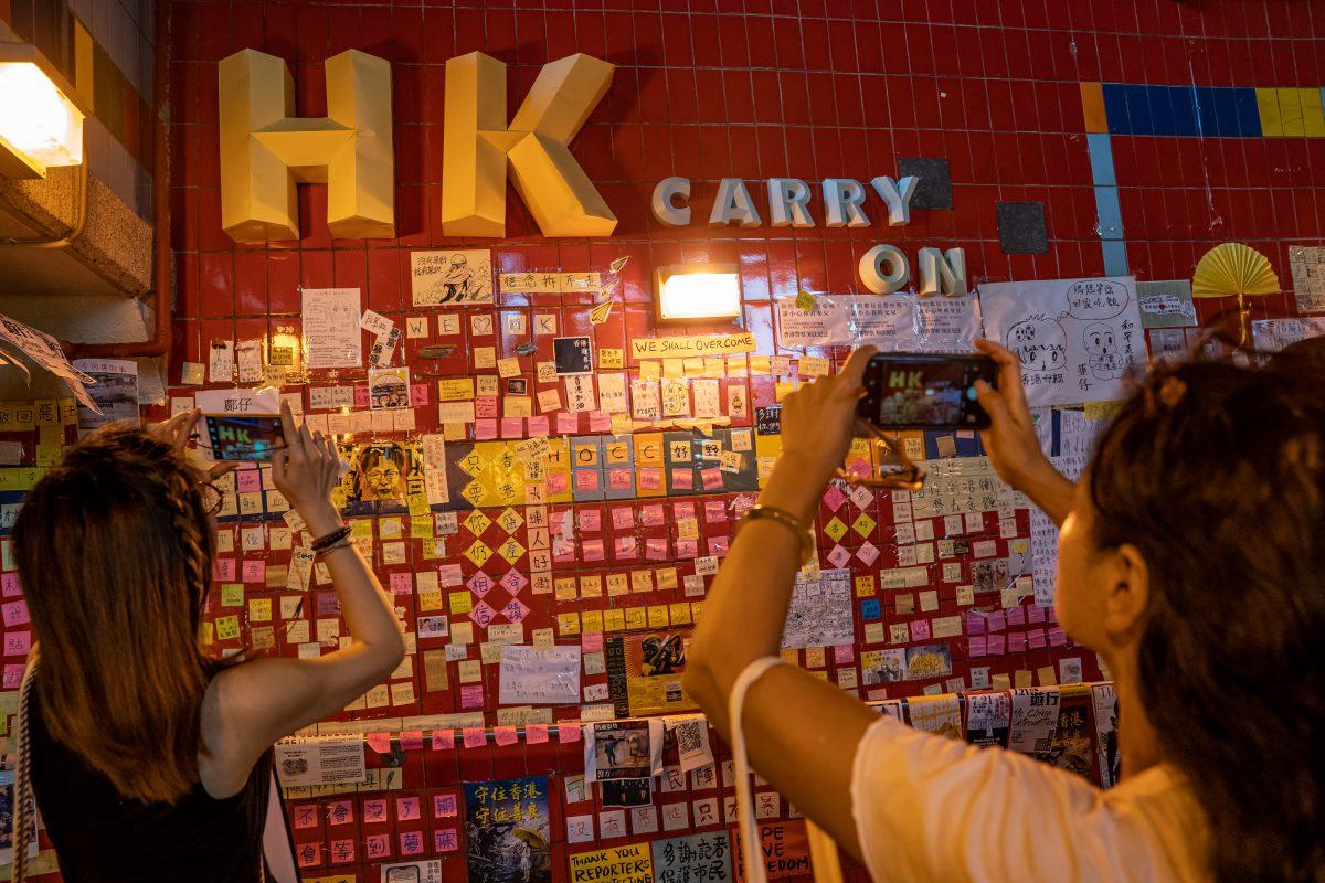 Pedestrians take photos at a makeshift "Lennon Wall" covered with handwritten messages to show support for the pro-democracy protesters, inside an underground tunnel at Tai Po district in Hong Kong, China, on July 20, 2019. (Anthony Kwan/Getty Images)