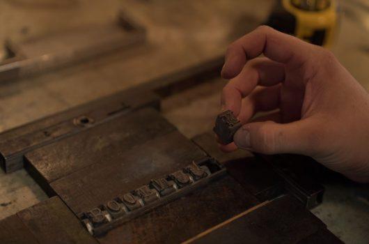 Robert Wilson sets letters for a bookmark into a metal frame. (Tal Atzmon/NTDTV)