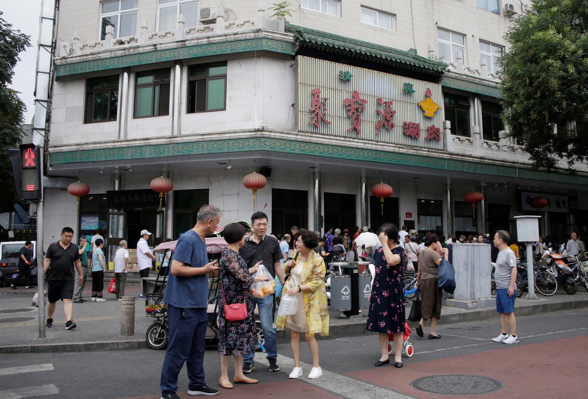 People stand outside a halal hotpot restaurant, which has had Arabic script removed from the signboard over its entrance, at Niujie area in Beijing on July 19, 2019. (Reuters)