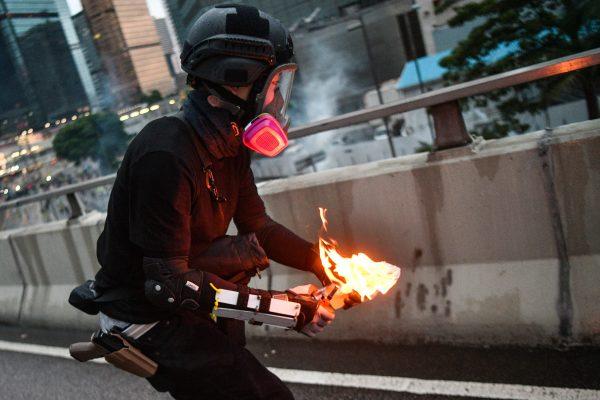 A black-clad man with holstered gun throws a molotov cocktail towards police outside the government headquarters in Hong Kong on Aug. 31, 2019. Some suspect the man of being an undercover police officer. (Anthony Wallace/AFP/Getty Images)