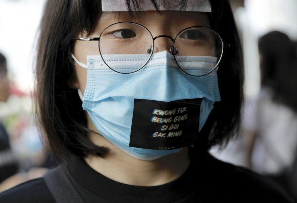 A woman wears a face mask with a sticker reading "Add oil Hong Kong people," a term of encouragement, during a demonstration at Edinburgh Place in Hong Kong on Aug. 22, 2019. (AP Photo/Vincent Yu)