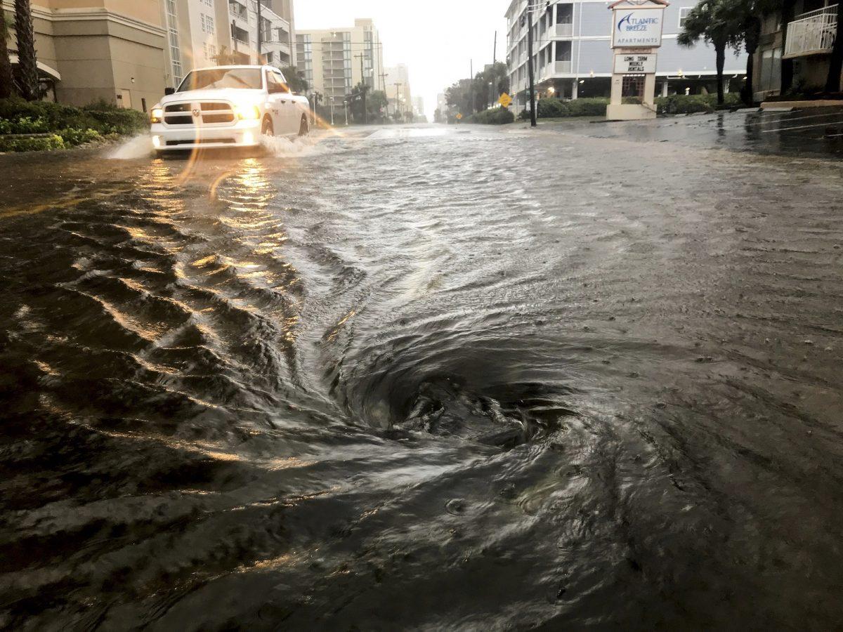 Floodwaters swirl around a storm drain as heavy rain falls from Hurricane Dorian in North Myrtle Beach, S.C., on Sept. 5, 2019. (Jason Lee/The Sun News via AP)