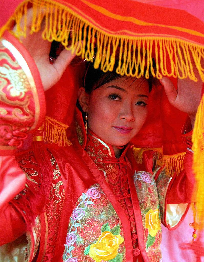 Illustration - Getty Images | <a href="https://www.gettyimages.com/detail/news-photo/performer-portraying-the-bride-of-a-manchu-nobleman-lifts-news-photo/52777145?adppopup=true">STR</a>