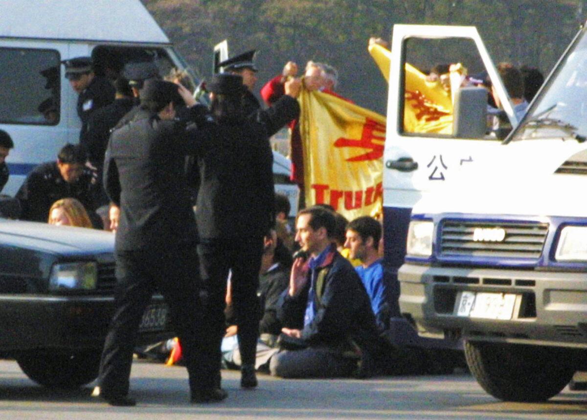 Westerners are surrounded by Chinese police officers and police vehicles in Tiananmen Square after unfurling a Falun Gong banner and sitting in a meditation position on Nov. 20, 2001. The group was later taken away and detained by police. (AP Photo/Ng Han Guan)