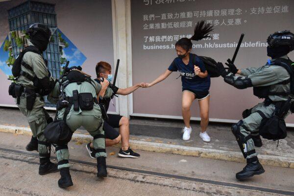 Hong Kong police chase down a couple wearing facemasks in the Central district in Hong Kong on Oct. 5, 2019. (Nicolas Asfouri/AFP/Getty Images)