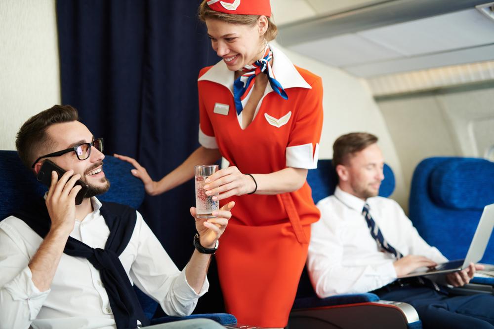 Illustration - Shutterstock | <a href="https://www.shutterstock.com/image-photo/portrait-smiling-flight-attendant-serving-glass-1192684219?src=_kWRmyYB51_VoJvgqcx3qg-1-5">SeventyFour</a>