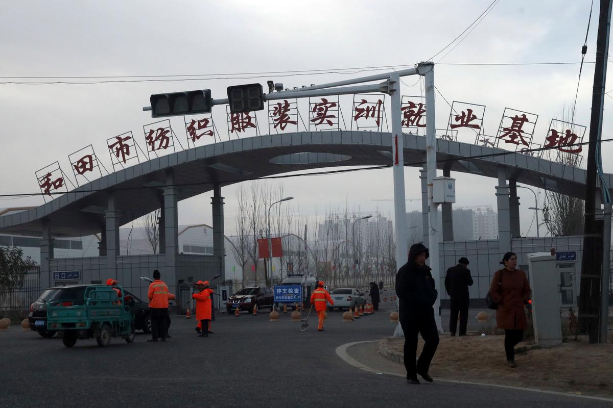 Residents pass by the entrance to the "Hotan City apparel employment training base" where Hetian Taida Apparel Co. has a factory in Hotan in western China's Xinjiang region, on Dec. , 2018. (Ng Han Guan/AP)