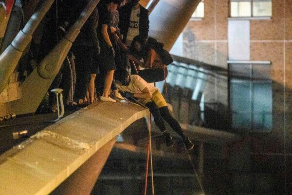 A protester prepares to lower himself down a rope from a bridge to a highway to escape from Hong Kong Polytechnic University campus and from police, in Hung Hom district in Hong Kong on Nov. 18, 2019. (Anthony Wallace/AFP via Getty Images)