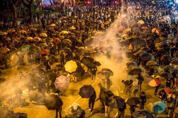 Protesters react as police fire tear gas while they attempt to march toward Hong Kong Polytechnic University in Hung Hom district of Hong Kong on Nov. 18, 2019. (Dale de la Rey/AFP via Getty Images)