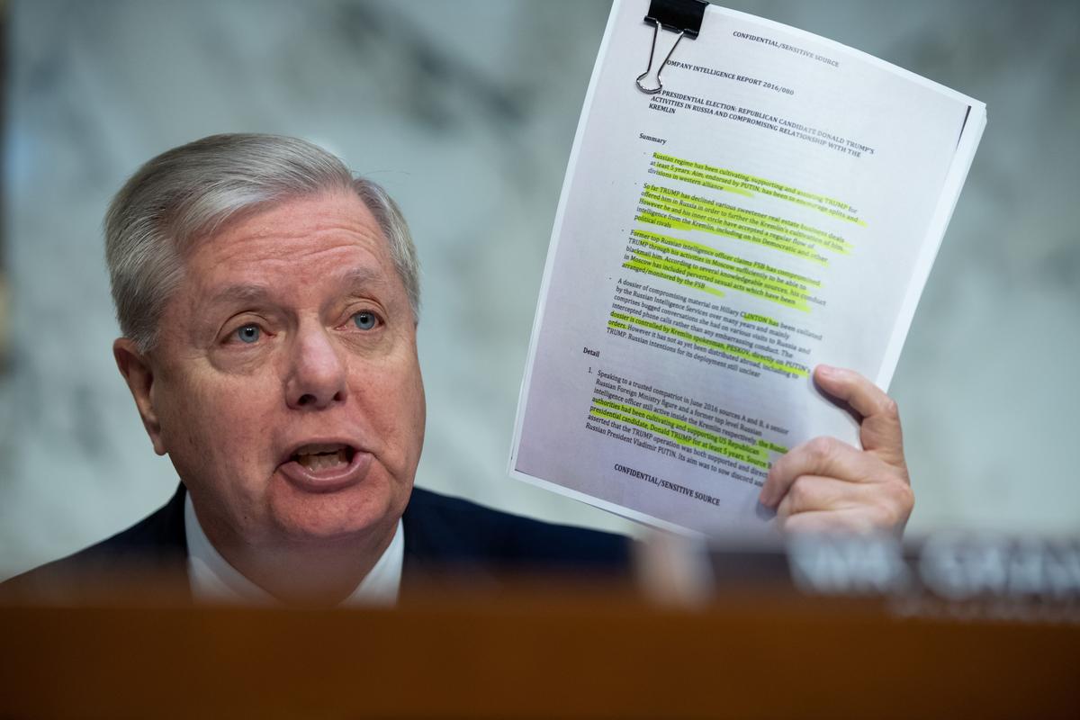 Senate Judiciary Chairman Lindsey Graham (R-S.C.) holds a copy of the Steele Dossier, as Justice Department Inspector General Michael Horowitz testifies about the Inspector General's report on alleged abuses of the Foreign Intelligence Surveillance Act (FISA) during a Senate Judiciary Committee hearing on Capitol Hill in Washington on Dec. 11, 2019. (Saul Loeb/AFP via Getty Images)