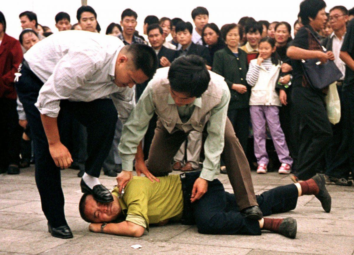 Chinese police arrest a Falun Gong practitioner in Tiananmen Square in Beijing as a crowd watches on Oct. 1, 2000. (Chien-min Chung/AP Photo)