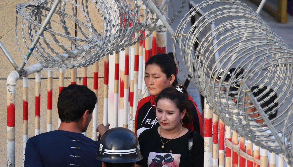 This photo taken on May 31, 2019 shows a Uighur woman (C) going through an entrance to a bazaar in Hotan, in China's northwest Xinjiang region. (Greg Baker/AFP via Getty Images)