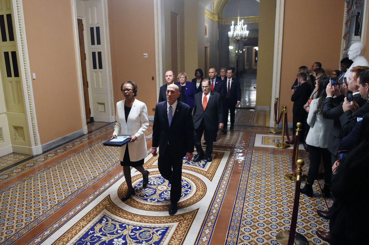The impeachment articles signed by House Speaker Nancy Pelosi being carried out by the House SAA Paul Irving (R) and House clerk Cheryl Johnson (L) over to the Senate side followed by impeachment managers on Capitol Hill in Washington on Jan. 15, 2020. (Olivier Douliery/AFP via Getty Images)