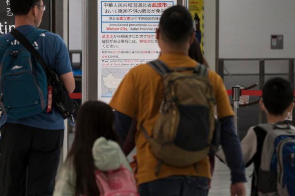 Passengers walk in front of a notice for passengers from Wuhan, China displayed near a quarantine station at Narita airport in Narita, Japan, on Jan. 17, 2020. (Tomohiro Ohsumi/Getty Images)