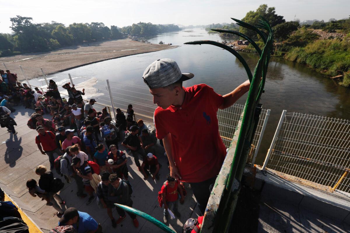 A migrant climbs the fence at the border crossing between Guatemala and Mexico in Tecun Uman, Guatemala, on Jan. 18, 2020. (Marco Ugarte/AP Photo)
