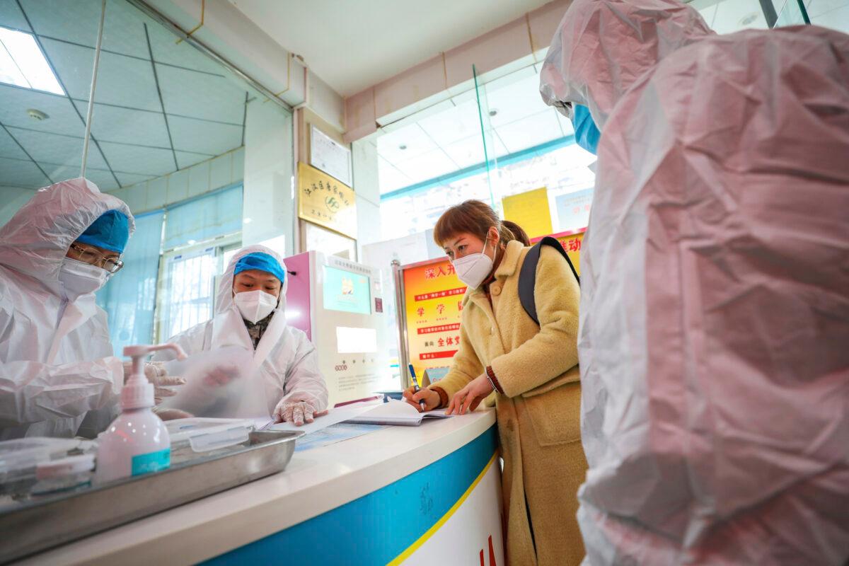Medical workers in protective gear talk with a woman suspected of being ill with a coronavirus at a community health station in Wuhan in central China's Hubei Province, on Jan. 27, 2020. (Chinatopix via AP)