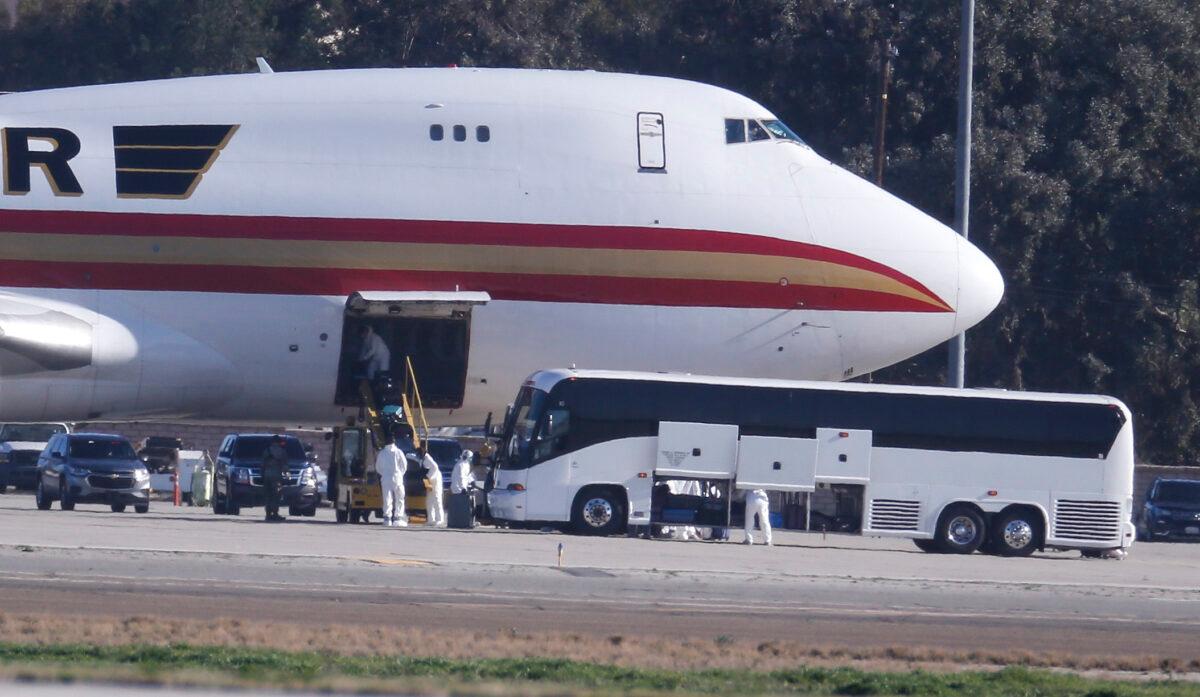 Personnel in protective clothing unload luggage from the airplane carrying U.S. citizens being evacuated from Wuhan, China, at March Air Reserve Base in Riverside, Calif. on Jan. 29, 2020. (Ringo H.W. Chiu/AP Photo)