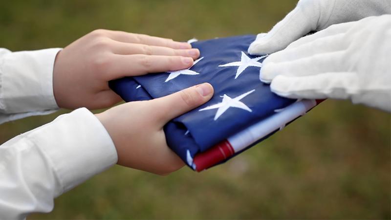Boy Uses His Body As a Shield When Friends Struggle to Fold American Flag on Windy Day