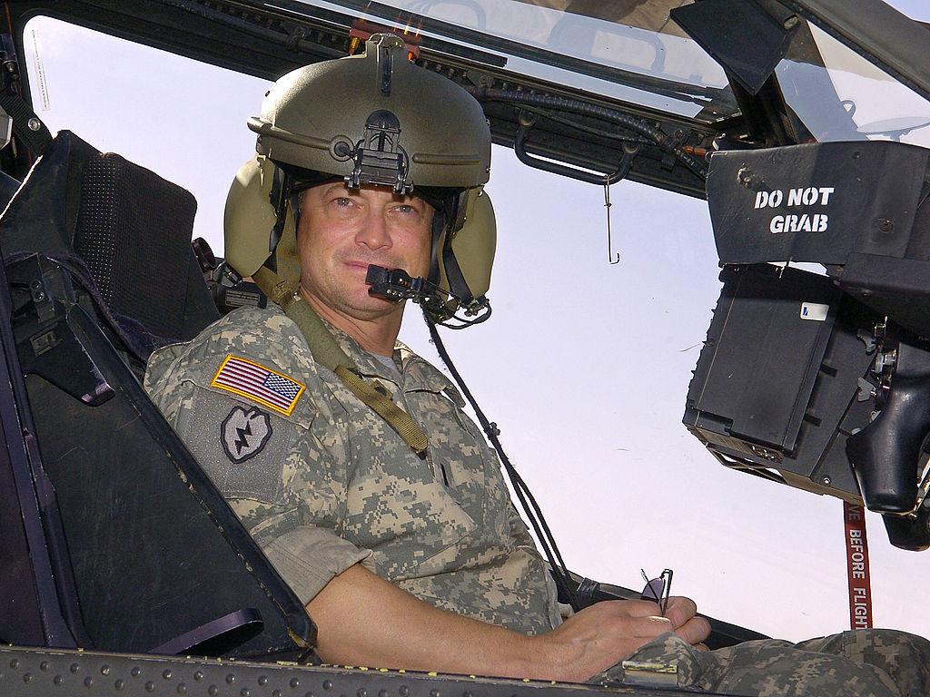 Gary Sinise sits in a U.S. Army Apache helicopter during a tour of the flight line on May 21, 2007, at Contingency Operating Base Speicher, Iraq. (©Getty Images | <a href="https://www.gettyimages.com/detail/news-photo/in-this-handout-provided-by-the-uso-actor-gary-sinise-sits-news-photo/74210351?adppopup=true">Mike Theiler/USO</a>)
