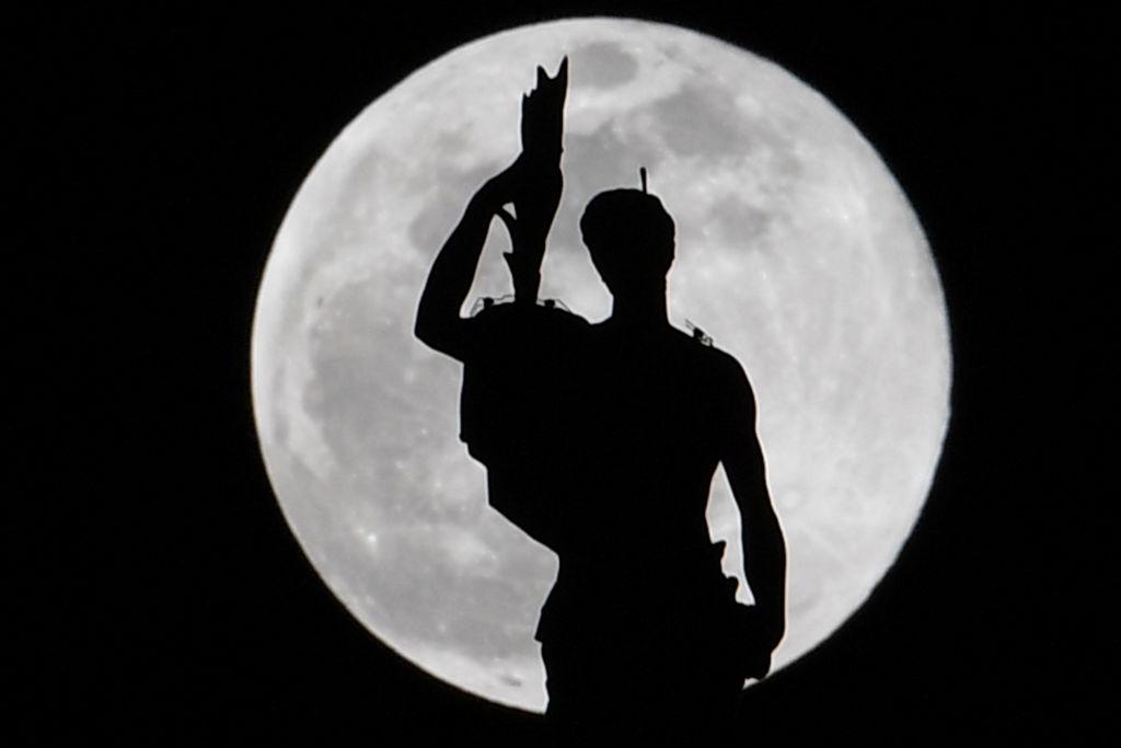 A statue atop Milan's Duomo Cathedral is pictured as the Super Snow Moon rises on Feb. 19, 2019. (©Getty Images | <a href="https://www.gettyimages.com/detail/news-photo/statue-atop-milans-duomo-cathedral-is-pictured-as-the-super-news-photo/1125887379?adppopup=true">ANDREAS SOLARO</a>)