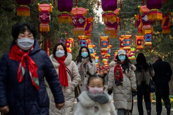 Residents wear protective masks as they walk under Chinese New Year decorations in a park in Beijing on Jan. 25, 2020. (Kevin Frayer/Getty Images)