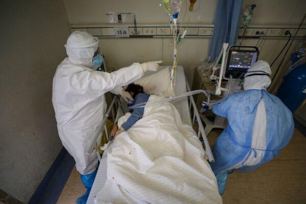 Medical workers in protective suits attend to a patient inside an isolated ward of Wuhan Red Cross Hospital in Wuhan, the epicenter of the novel coronavirus outbreak, in Hubei Province, China, on Feb. 16, 2020. (China Daily via Reuters)
