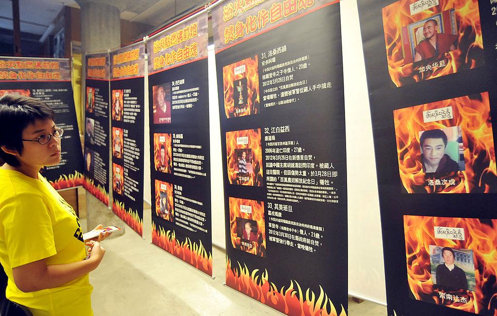 A woman at an exhibition showing portraits of reported self-immolation victims in Tibet, presented by Amnesty International's Taiwan branch in Taipei on June 29, 2012.  (©Getty Images | <a href="https://www.gettyimages.com/detail/news-photo/woman-looks-at-an-exhibition-showing-portraits-of-reported-news-photo/147400641">Mandy Cheng/AFP</a>)
