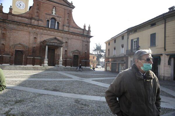 A man wearing a mask stands in front of the San Biagio church in Codogno, near Lodi, Northern Italy on Feb. 22, 2020. (Luca Bruno/AP Photo)
