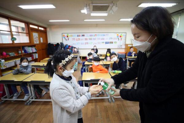 A teacher dispenses hand sanitizer to a student at Yongsan elementary school in Seoul on Jan. 30, 2020. (Park Dong-ju/Yonhap via AP)