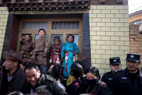 Children in traditional Tibetan clothes and police watch passing Tibetan Buddhist monks during a ceremony for Monlam, otherwise known as the Great Prayer Festival of Losar, the Tibetan New Year, at the Rongwo Monastery, in Tongren County, Huangnan Tibetan Autonomous Prefecture, on the Qinghai-Tibet plateau, on March 1, 2018. (Johannes Eisele/AFP via Getty Images)