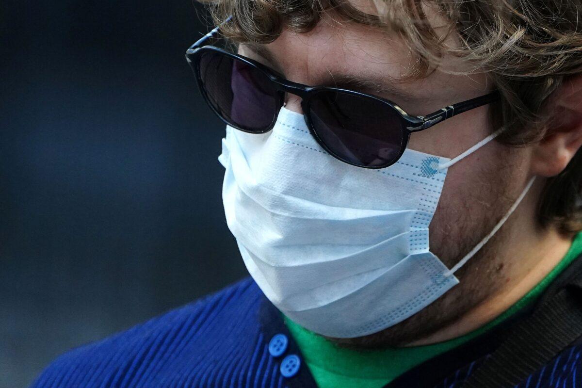 A man wearing a mask to protect against coronavirus takes pictures at the New York Stock exchange (NYSE) in the Manhattan borough of New York City, New York on March 9, 2020. (Carlo Allegri/Reuters)
