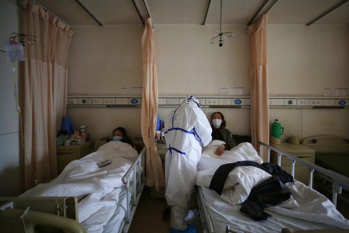 A medical staff member treats a patient infected by the COVID-19 coronavirus at Red Cross Hospital in Wuhan, China on March 11, 2020. (STR/AFP via Getty Images)