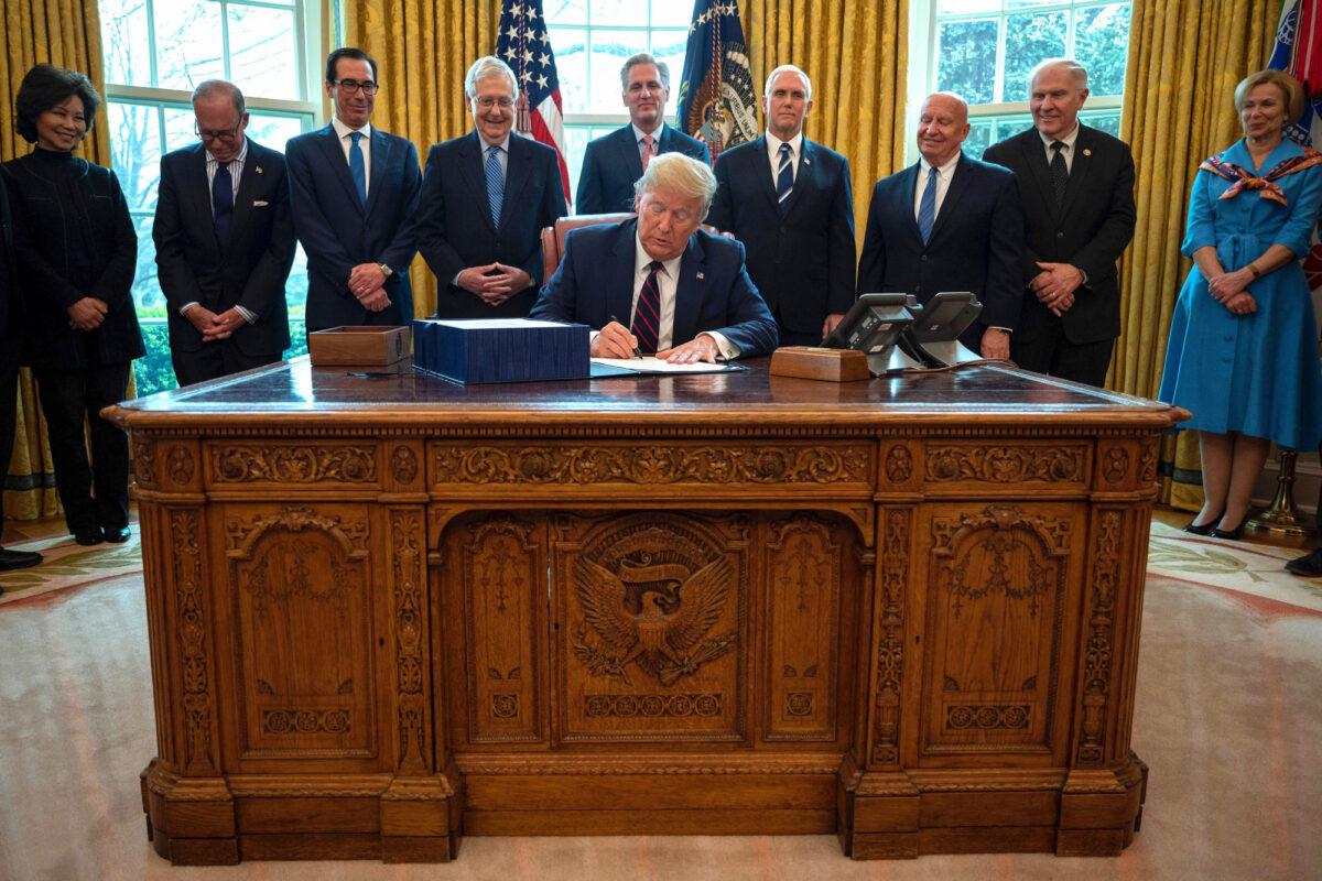 President Donald Trump signs the CARES act, a $2.2 trillion rescue package to provide economic relief amid the CCP virus outbreak, at the Oval Office of the White House on March 27, 2020. (Jim Watson/AFP via Getty Images)