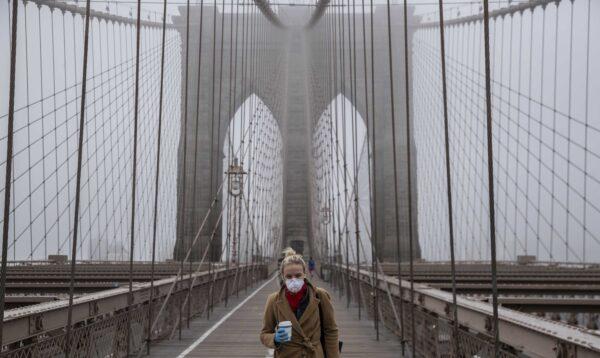A woman wearing a mask walks the Brooklyn Bridge in the midst of the CCP virus outbreak in New York City on March 20, 2020. (Victor J. Blue/Getty Images)