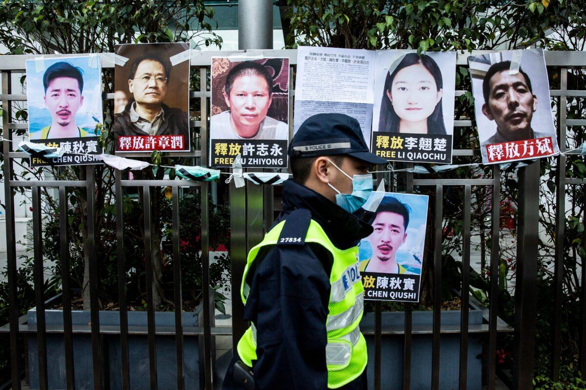 Police officer walks past placards of detained rights activists taped on the fence of the Chinese liaison office, in protest against Beijings detention of prominent anti-corruption activist Xu Zhiyong, in Hong Kong, China, on Feb. 19, 2020. (Isaac Lawrence/AFP via Getty Images)