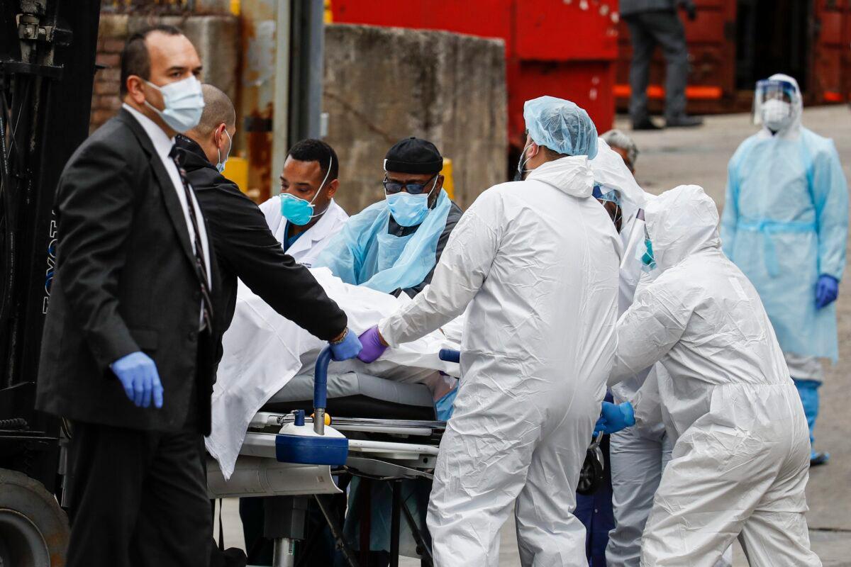 A body wrapped in plastic that was unloaded from a refrigerated truck is handled by medical workers wearing personal protective equipment due to COVID-19 concerns at Brooklyn Hospital Center in New York on March 31, 2020. (John Minchillo/AP Photo)