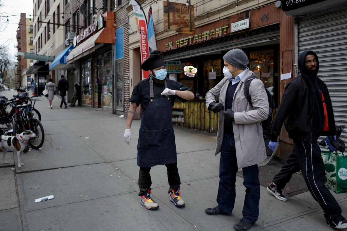Chef Jorge Cardenas shares an elbow bump with regular Ix customer Lorenzo Bernasconi outside of Ix restaurant in the Brooklyn borough of New York City, U.S., on April 2, 2020. (Anna Watts/Reuters)