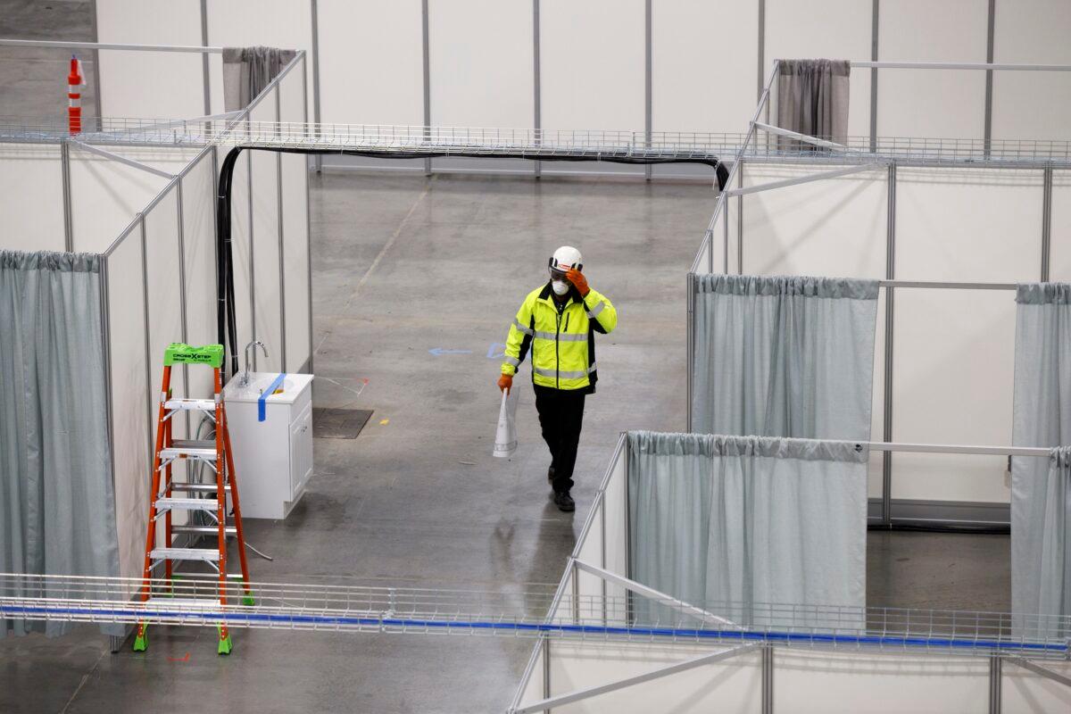 A worker walks by rows of beds in a convention hall at the Suburban Collection Showplace, which is being converted into a field hospital to treat CCP virus patients in Novi, Michigan, on April 11, 2020. (Elaine Cromie/Getty Images)