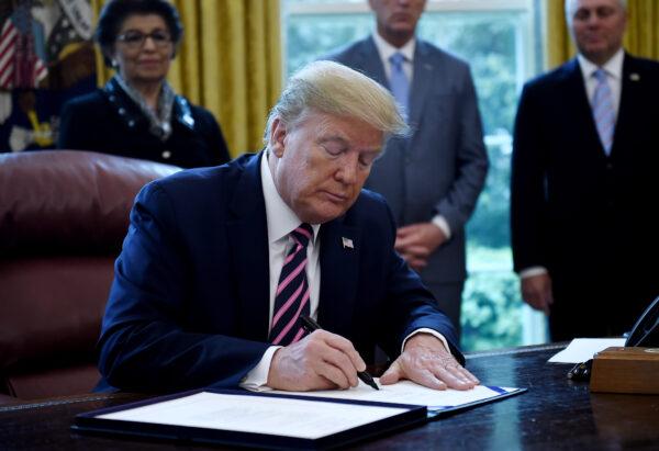 President Donald Trump signs the Paycheck Protection Program and Health Care Enhancement Act in the Oval Office of the White House in Washington, on April 24, 2020. (Olivier Douliery/AFP/Getty Images)