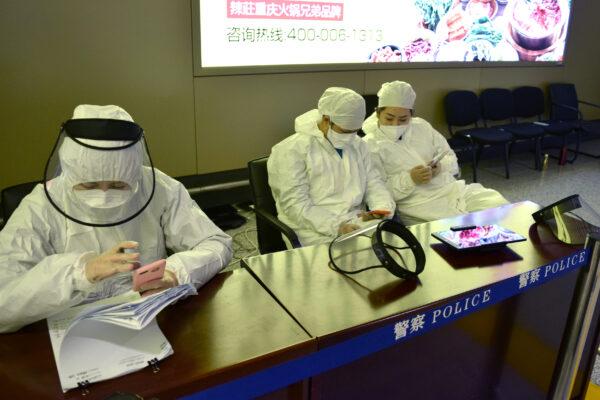 Workers in protective suits are seen at a registration point for passengers at an airport in Harbin, capital of China's Heilongjiang province bordering Russia, following the spread of the CCP virus in the country, on April 11, 2020. (Huizhong Wu/Reuters)