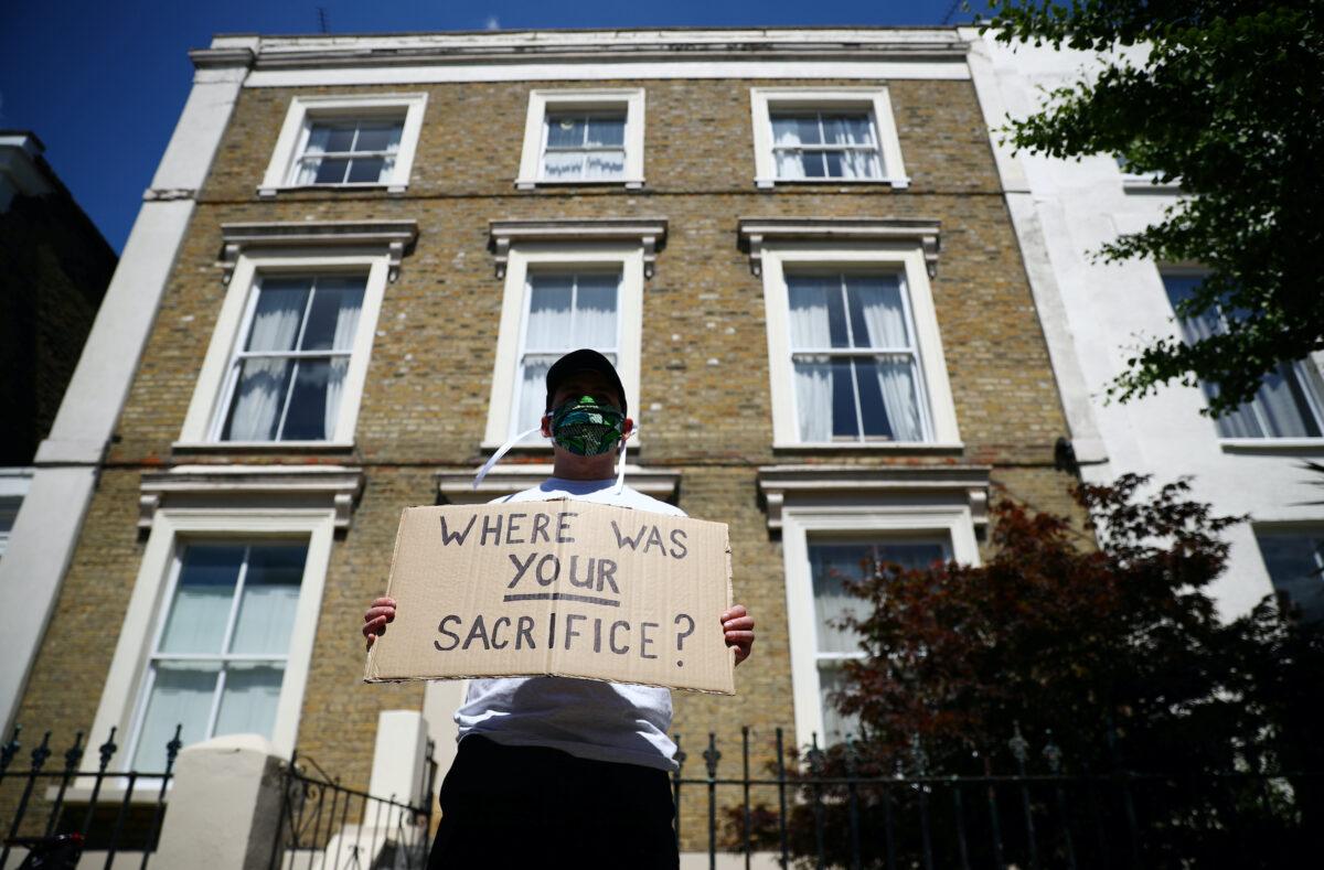 A protestor wearing a protective face mask is seen displaying a message near the house of Dominic Cummings, special advisor for Britain's Prime Minister Boris Johnson following the outbreak of COVID-19, London, Britain, on May 25, 2020. (Hannah McKay/Reuters)