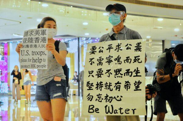 Two protesters hold up signs as they take part in a protest at IFC shopping mall in Hong Kong on May 25, 2020. (Song Bilung/The Epoch Times)